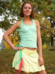 Slim teen girl takes off green top, yellow skirt and white panties.