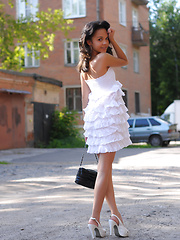 Adorable dark haired teen chick demonstrating her excellent body under white dress outdoors.