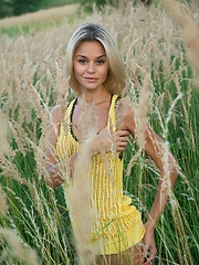With a confident, charming allure, Taylor is a stunning sight as she strips her hot yellow dress amidst the tall, verdant grass and tree.